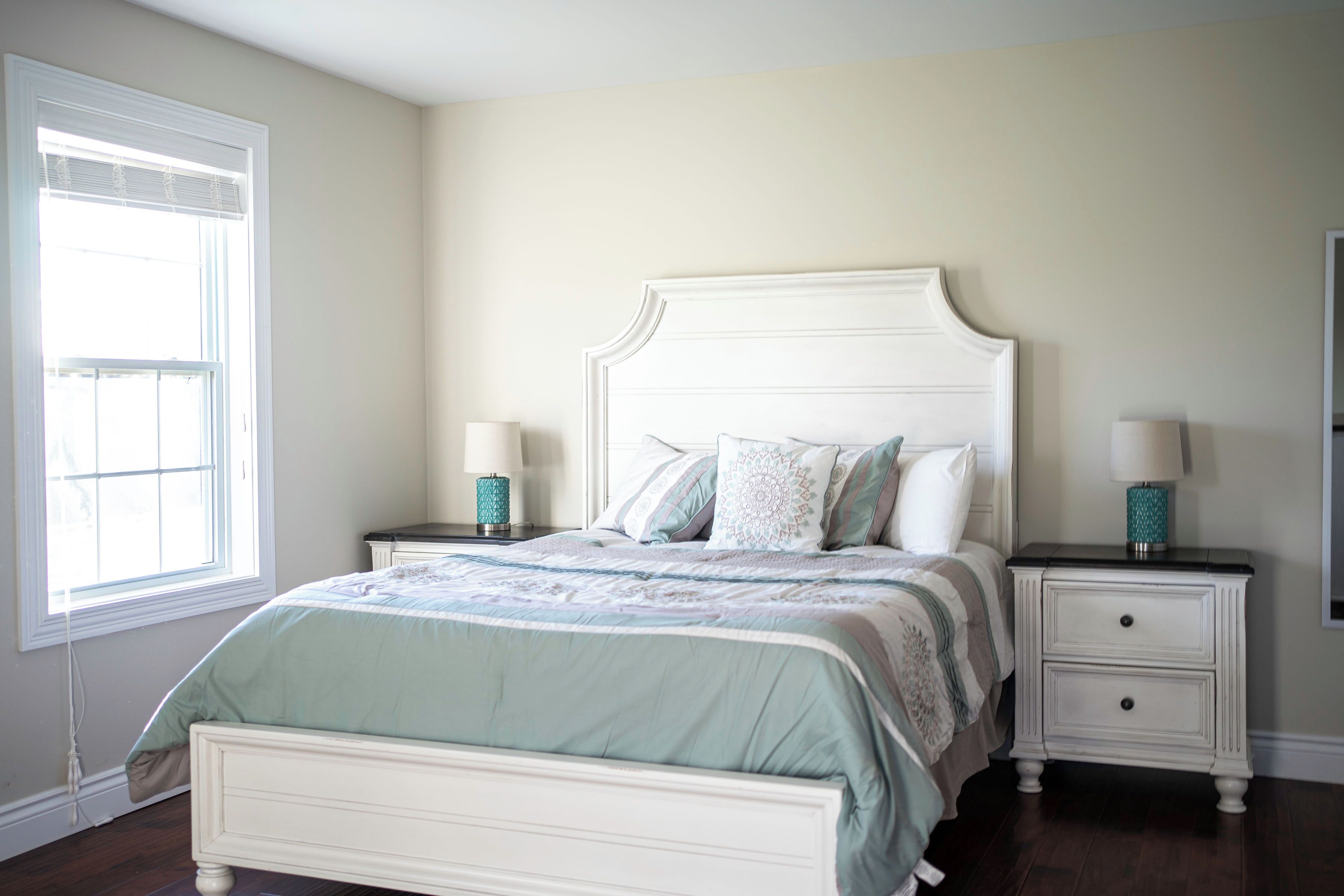A bedroom with a bed, two bedside tables, a window, and a nightstand.