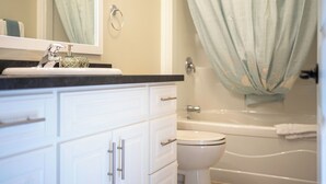 A bathroom with a sink, mirror, toilet, and bathtub.
