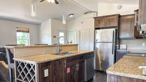 A modern kitchen with dark wood cabinets, stainless steel appliances, and a granite countertop.