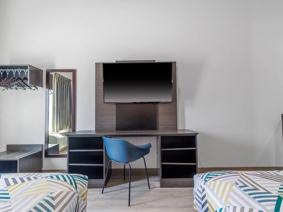 Une chambre à coucher comprenant un lit, un bureau, une chaise, une télévision et une armoire.