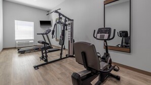A modern gym with cardio machines, weight training equipment, and a large mirror. - Motel 6 Gonzales, La - Baton Rouge/Geismar/Prairieville I-10 (Gonzales)