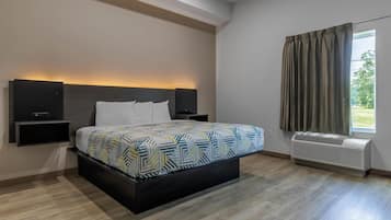 Una habitación de hotel moderna con una cama grande, altavoces integrados, una ventana con cortinas y un equipo de aire acondicionado.