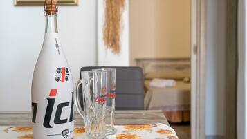 A bottle of ICI wine, two glasses, and a table with a floral tablecloth.