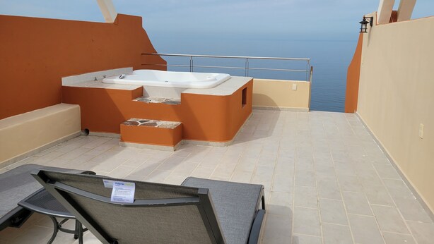 A balcony with a hot tub, a chair, and a view of the sea. - Incredible views!! 1 bedroom condo with large terrace #504 at Vista Encantada! (El Divisadero)