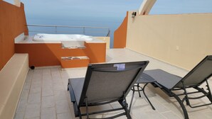 A balcony with a hot tub, two chairs, and a view of the sea. - Incredible views!! 1 bedroom condo with large terrace #504 at Vista Encantada! (El Divisadero)
