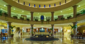 A spacious lobby with a central fountain, multiple levels with balconies, and a reception desk.