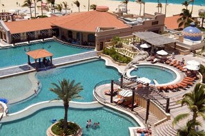 A resort with multiple swimming pools, sun loungers, and a covered area.
