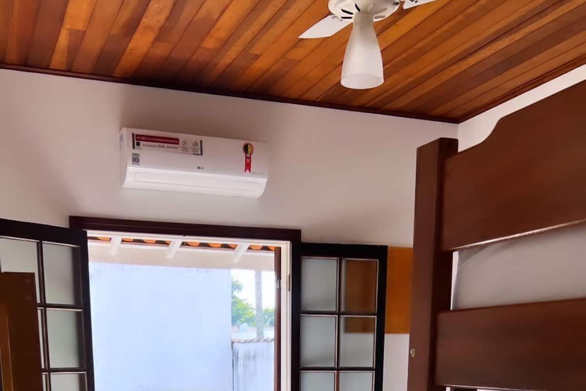 A room with a bed, a ceiling fan, and a view of a balcony with a railing.