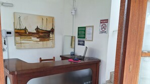 Een receptiebalie met een laptop, een schilderij en een rookvrij bord.