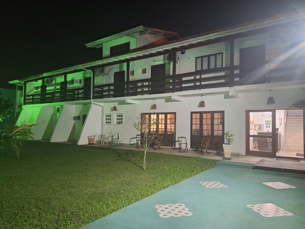 A two-story building with a balcony, outdoor seating, and a well-maintained lawn.
