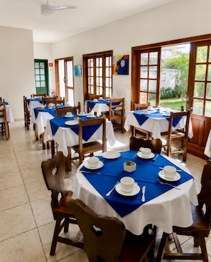 A dining area with round tables, each set with white plates, bowls, and cutlery. - Pousada Ubatuba Itaguá (Ubatuba)