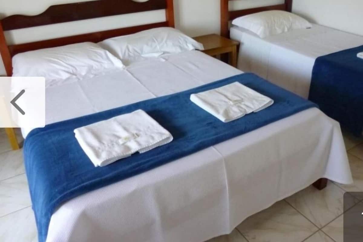A hotel room with two beds, each with white bedding and a blue blanket. There are two white towels folded on the beds.