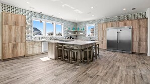 Una cocina moderna con una isla central, armarios de madera y un refrigerador de acero inoxidable.