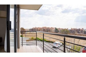 Enjoy a view of the surrounding residential area from this balcony with a metal railing and tiled floor.