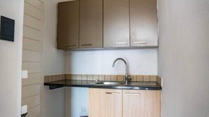 Compact kitchen with a sink and countertop, featuring a wall-mounted outlet.
