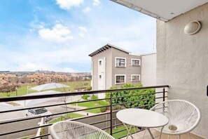 Enjoy a peaceful view from this balcony with a table and two chairs.