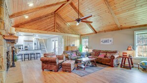 Amplia sala de estar con techo alto, vigas de madera, chimenea y vistas al área de cocina y comedor.