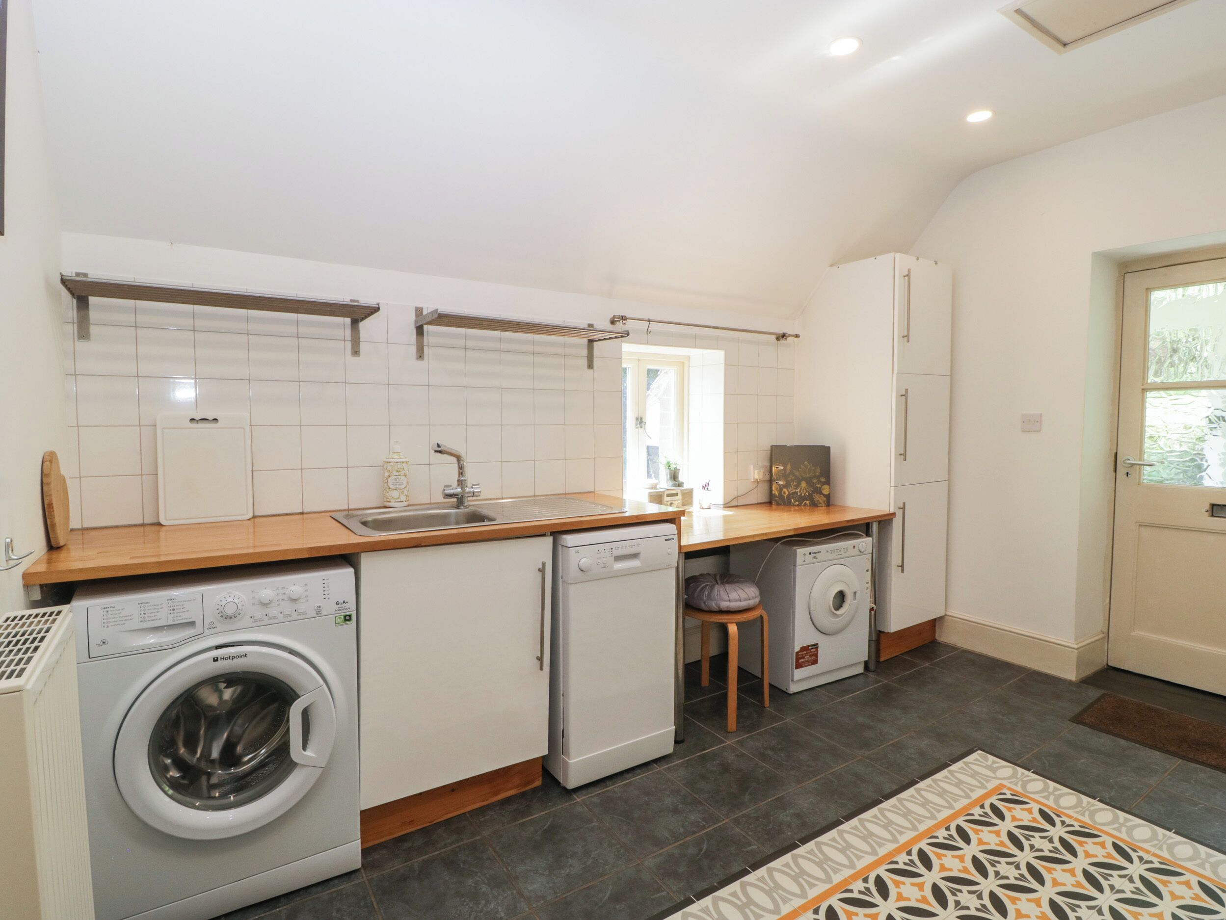 Een kleine keuken met een wasmachine, een vaatwasser en een spoelbak.