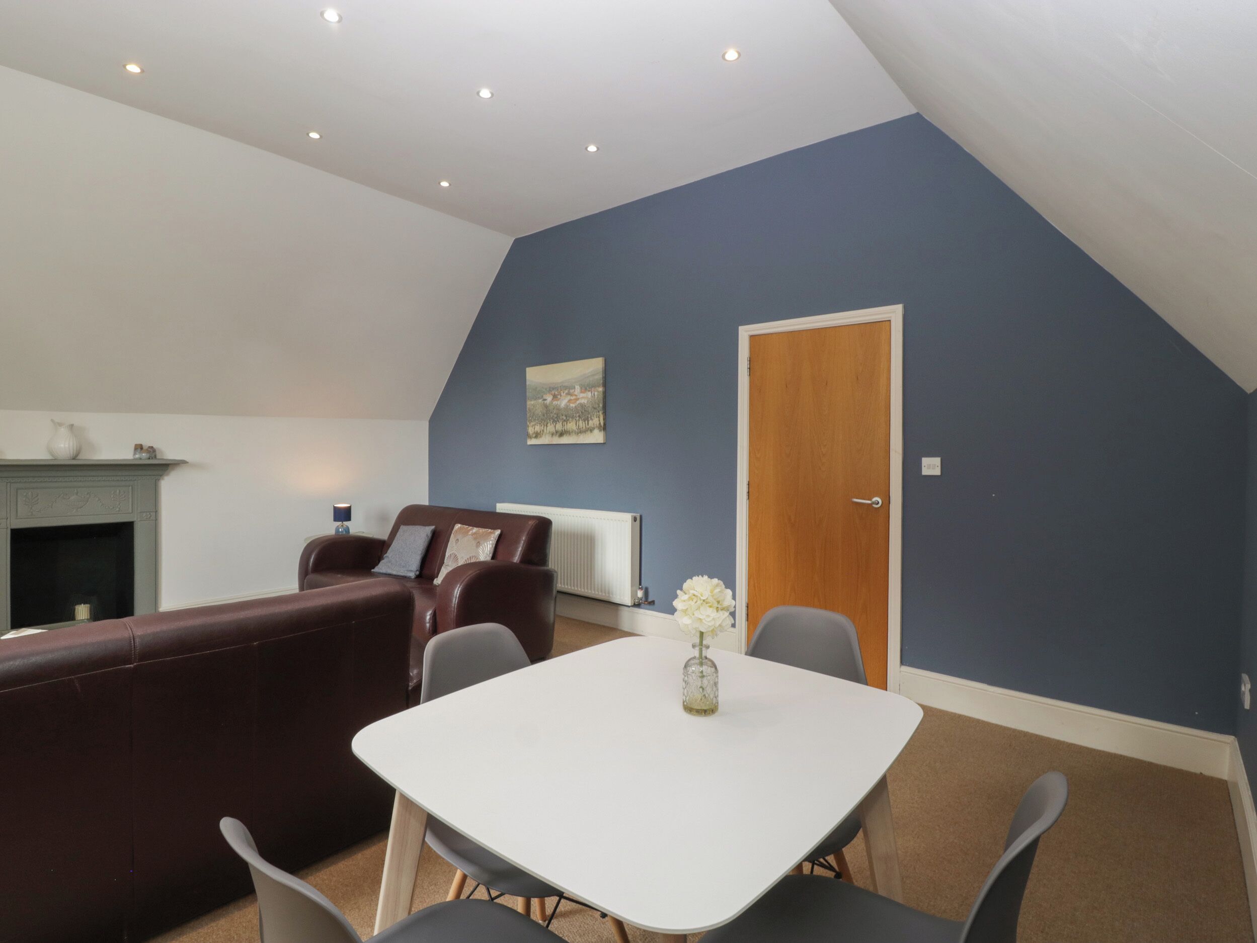 Un salon avec une table blanche, un canapé marron et un mur bleu.