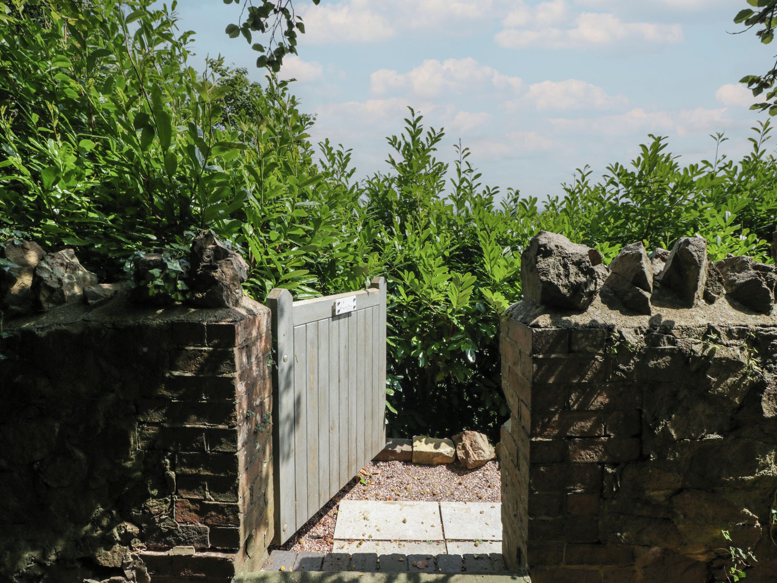 A stone gate with a wooden door, surrounded by lush green foliage.