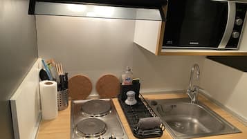 Een koelkast, een microgolfoven, een oven, kookgerei, borden en bestek