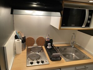 Een koelkast, een microgolfoven, een oven, kookgerei, borden en bestek