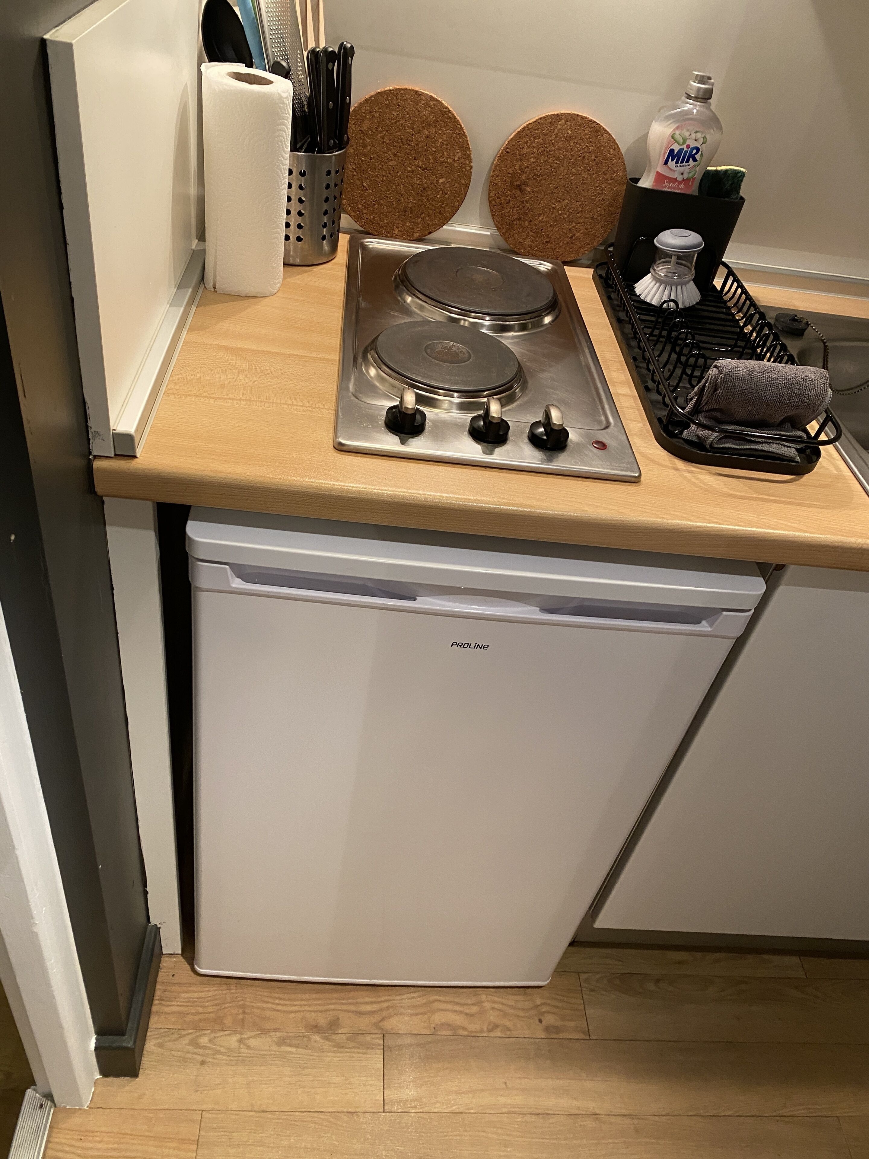 A compact kitchen with a stainless steel stove, a white dishwasher, and a wooden countertop.