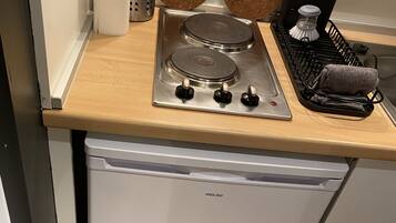 A compact kitchen with a stainless steel stove, a white dishwasher, and a wooden countertop.