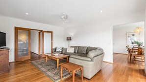 A modern living room with a sofa, coffee table, and TV stand. - Lonnie Getaway - Point Lonsdale (Point Lonsdale)