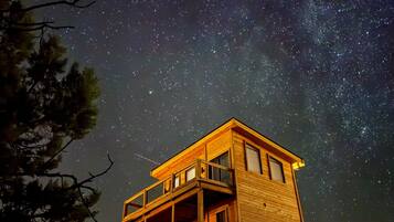 Una cabaña de madera con balcón, al pie de un cielo estrellado.