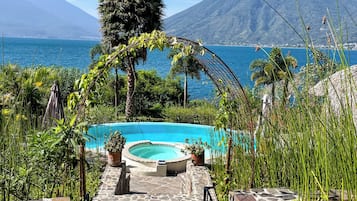Un sendero de piedra que conduce a una piscina circular, con vista a una montaña y al mar.