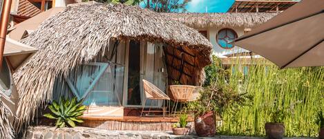 Un espacio al aire libre con techo de paja, muebles de mimbre y plantas en macetas.
