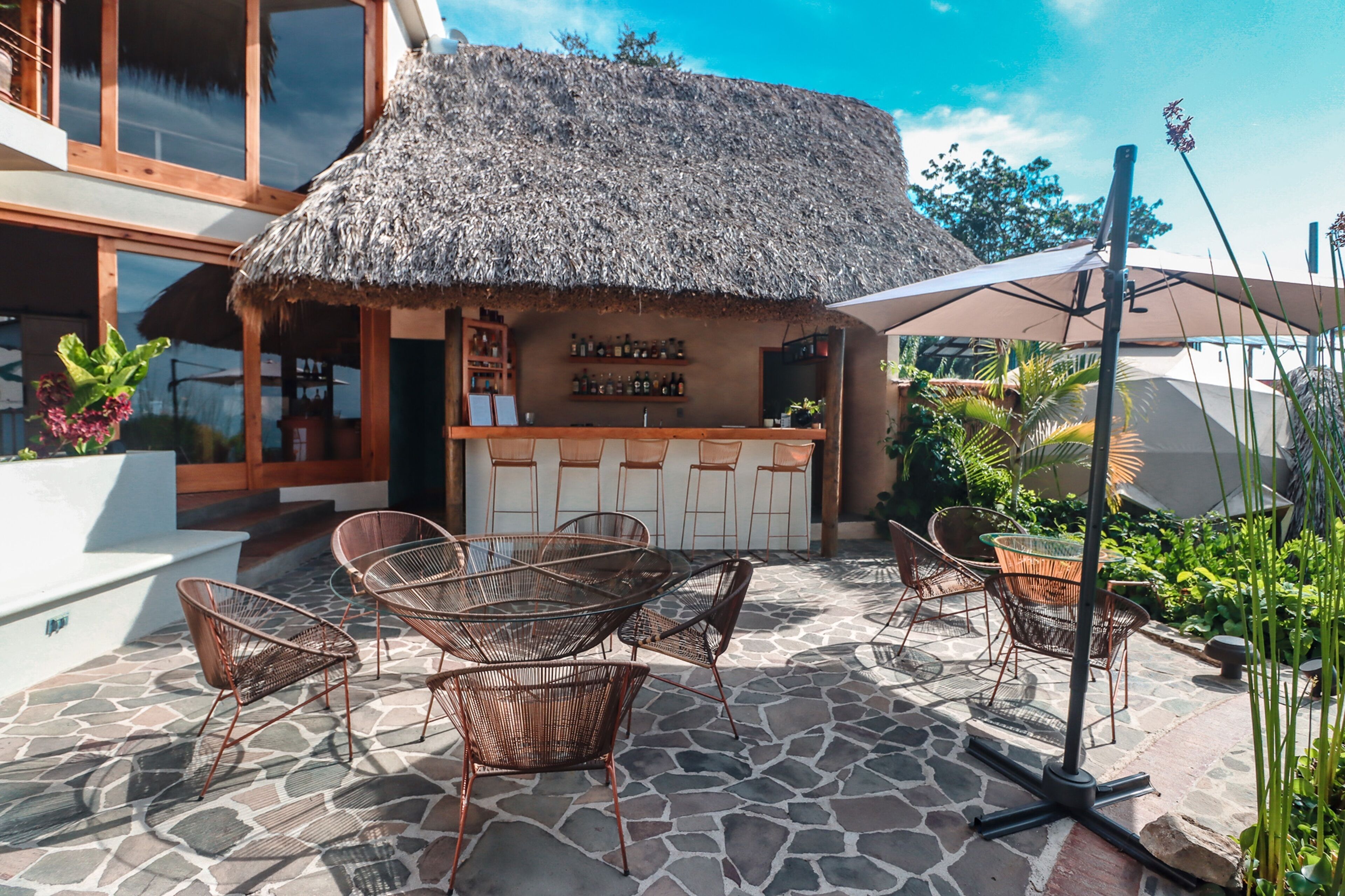 An outdoor seating area with wicker chairs and a thatched-roof bar.