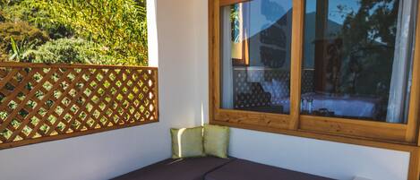 A cozy seating area with a wooden table, large windows, and a view of greenery.