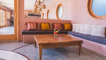 A modern interior with a wooden coffee table, a sofa with patterned cushions, and a large mirror on the wall.
