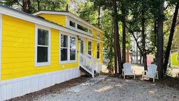 A yellow building with a white porch and a gravel driveway.