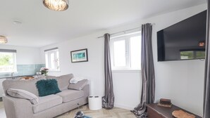 A modern living room with a sofa, coffee table, and a television mounted on the wall. - Duart At The Sea (Wick)