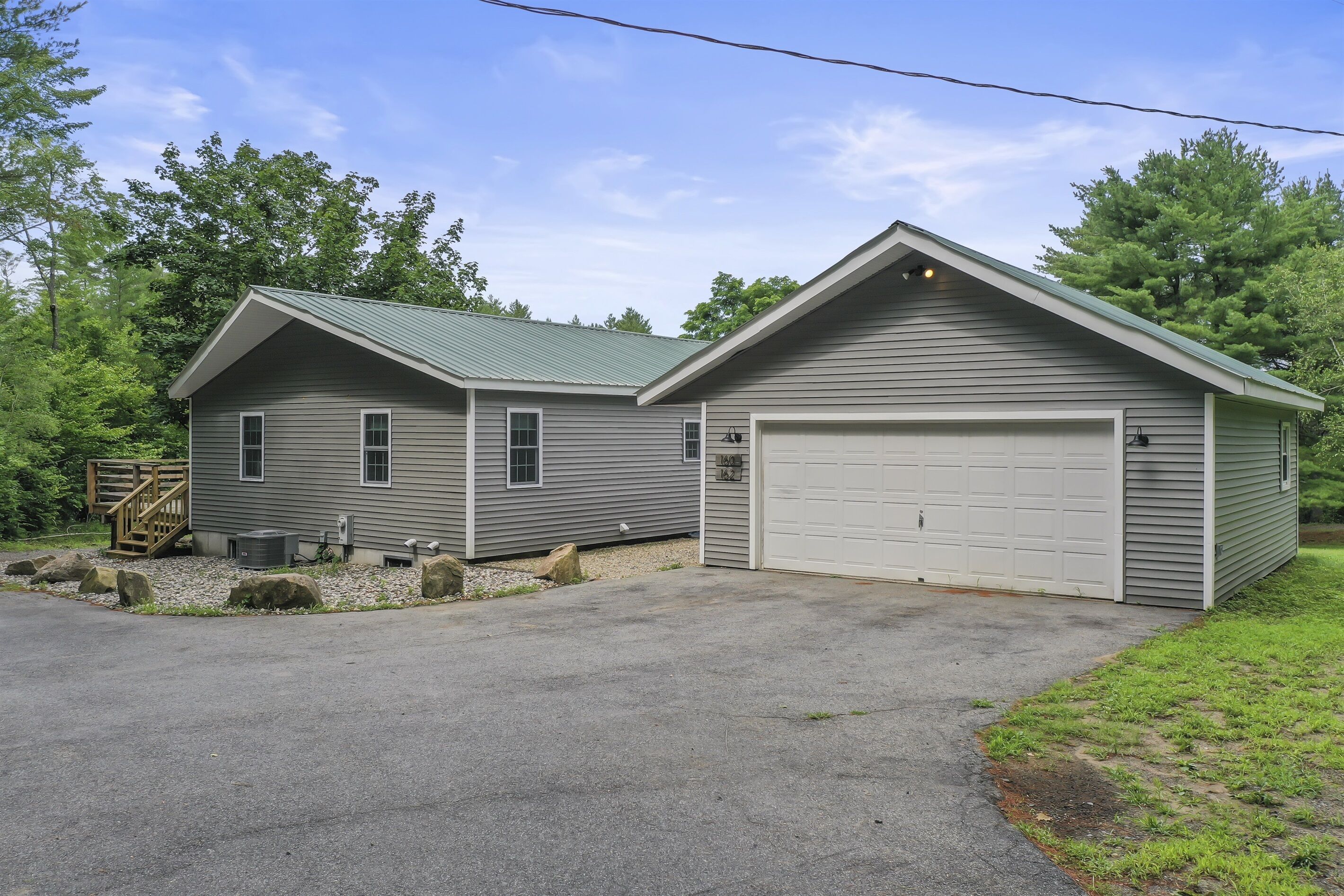 A two-story house with a garage, a covered porch, and a stone pathway leading to the entrance.