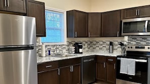 Una cocina moderna con armarios de madera oscura, electrodomésticos de acero inoxidable y salpicadero de azulejos.