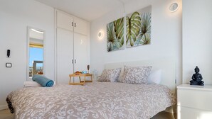 A bedroom with a bed, a nightstand, a mirror, a painting, and a wardrobe. - 'Salou Beach' Apartment with Sea View, Wi-Fi and Air Conditioning (Salou)