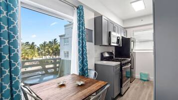 A compact kitchen with modern appliances, a dining area with a view, and a balcony with a railing.