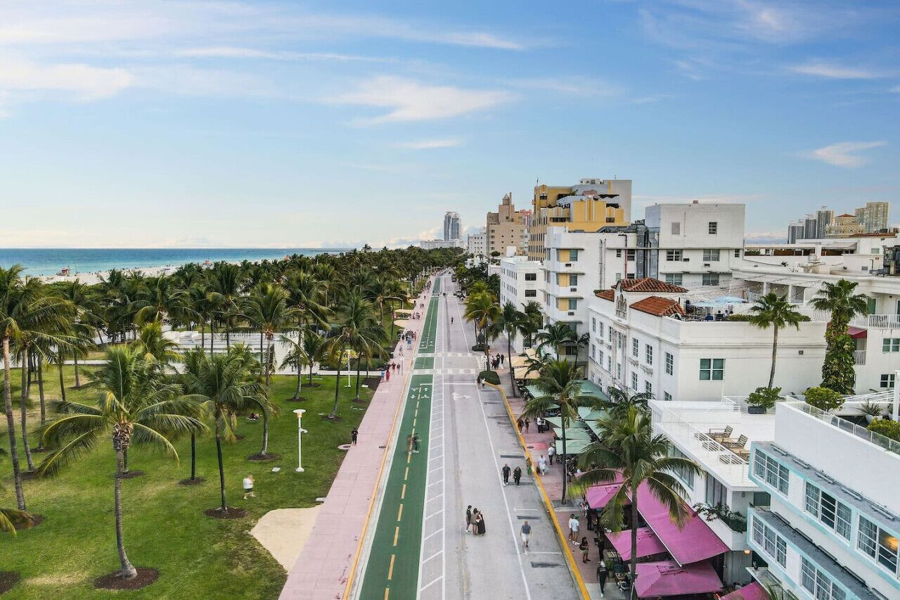 A coastal urban area with a wide street lined with palm trees and buildings.
