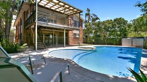A swimming pool with a covered patio area, a staircase leading to a second floor, and a fenced garden area. - Generous Family Home with 4 Bedrooms, Pool, Pet Friendly (Sunshine Beach)