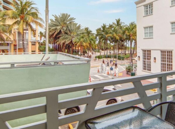 A balcony with a view of palm trees and a building with a white facade.
