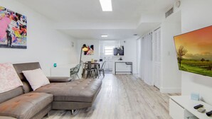 A modern living room with a sectional sofa, a dining area, and a kitchen in the background. - 2B/2B, Free Parking, South Beach, 1 Block 2 Beach (South Beach)