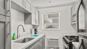 Una cocina moderna con un lavabo, estufa y ventana con persianas.