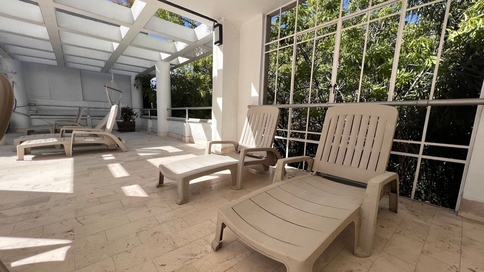 Un’area salotto esterna illuminata dal sole, con poltrone relax e una pergola.