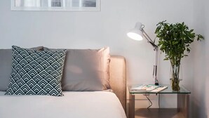 A neatly arranged bedroom with a bed, pillows, a bedside table with a lamp, and a potted plant. - Condesa Residence Campeche 276 (Mexico City)