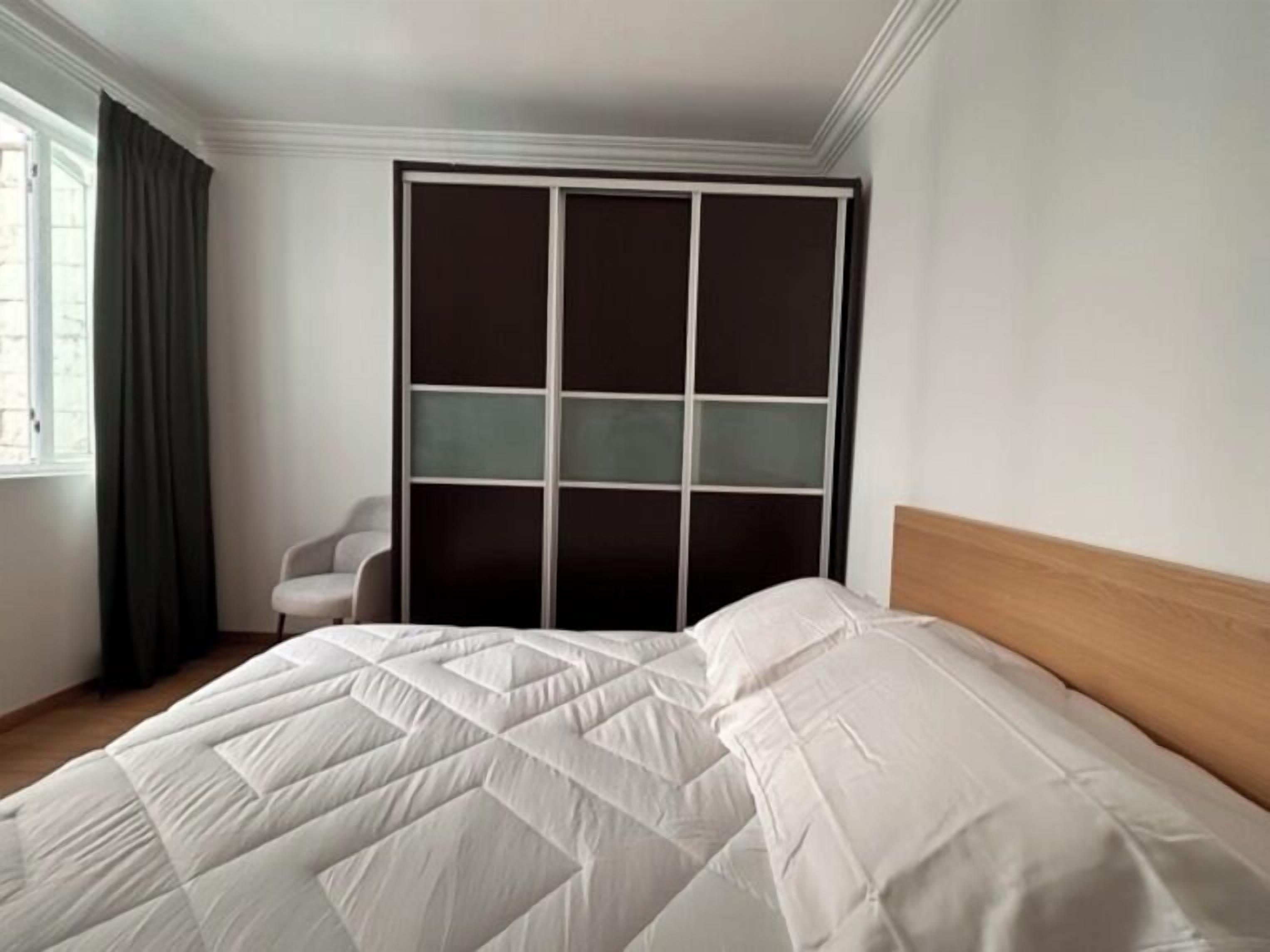 Un dormitorio con cama, una silla y un armario.