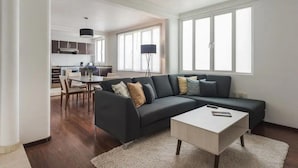 A modern living room with a dark sofa, a white coffee table, and a dining area with a table and chairs. - Condesa Residence Campeche 276 (Mexico City)